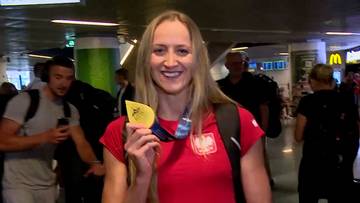 Katarzyna Wasick, polska pływaczka, trzyma złoty medal i uśmiecha się do kamery. Ma na sobie czerwoną koszulkę z godłem Polski.