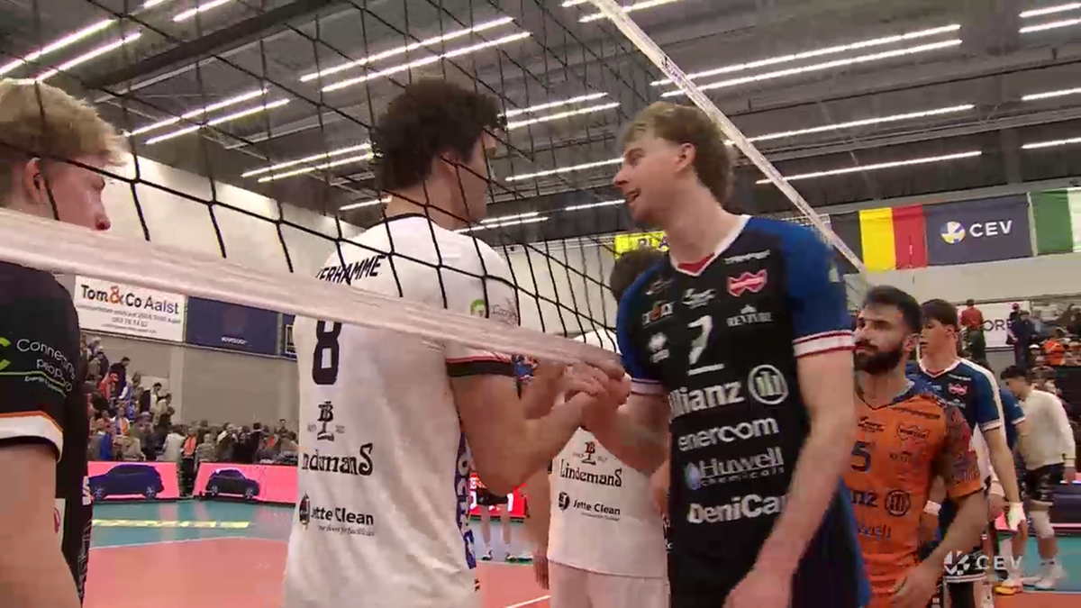 Dw&oacute;ch siatkarzy po meczu ściska sobie dłonie nad siatką.