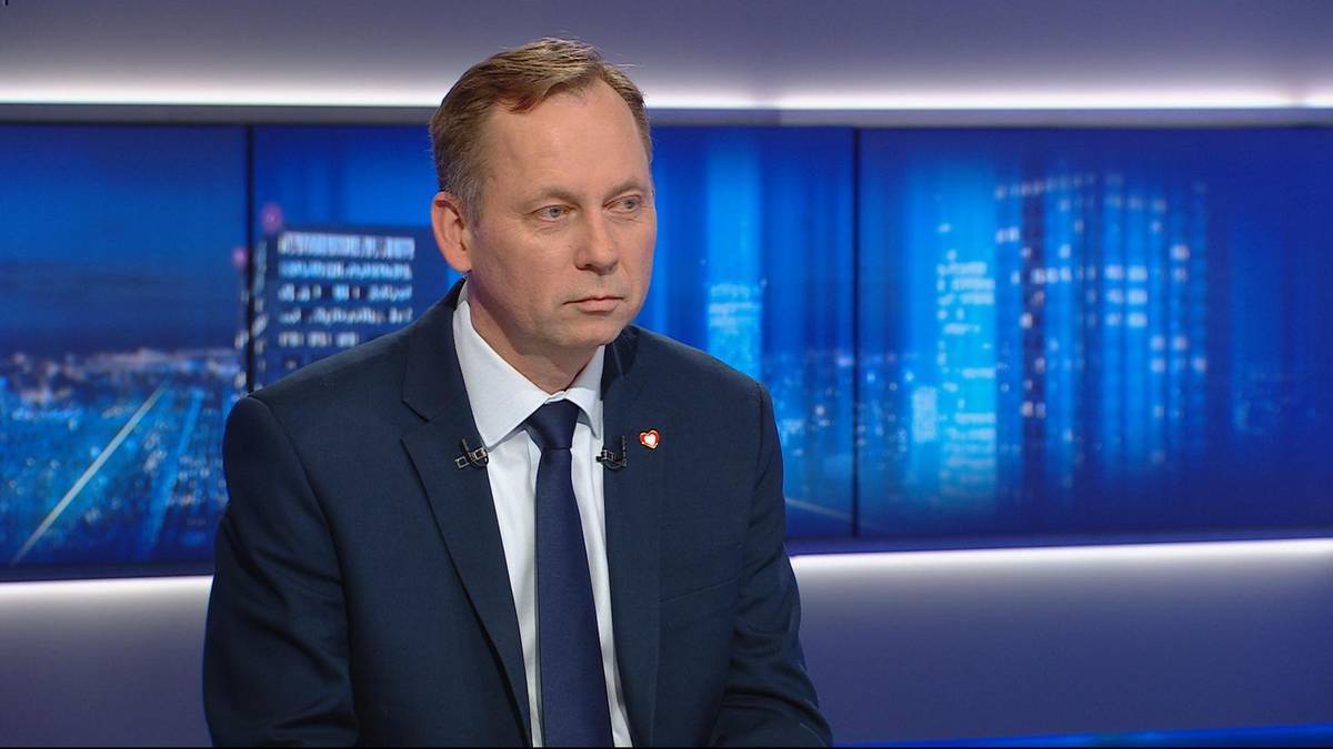 Mężczyzna w garniturze siedzi przed ekranem z widokiem na nocne miasto.