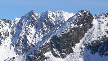 Zimowy krajobraz Tatr z ośnieżonymi szczytami i błękitnym niebem.