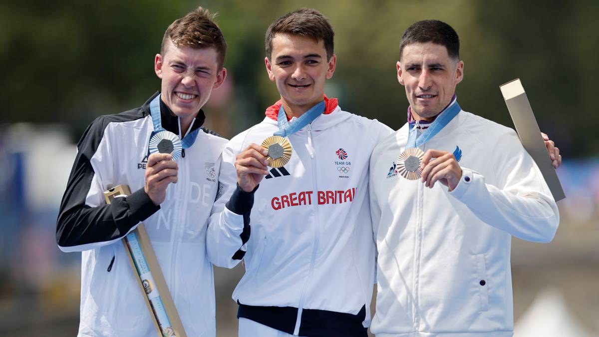 Trzech młodych mężczyzn pozuje do zdjęcia na podium sportowym, każdy z medalem na szyi. Pierwszy od lewej trzyma srebrny medal, drugi, środkowy, ma złoty medal i nosi białą bluzę z napisem "GREAT BRITAIN", a trzeci od prawej prezentuje brązowy medal.