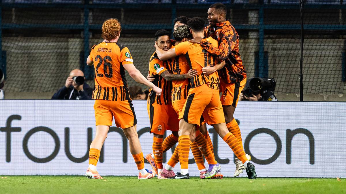 Grupa piłkarzy w pomarańczowych strojach świętuje gola na boisku.