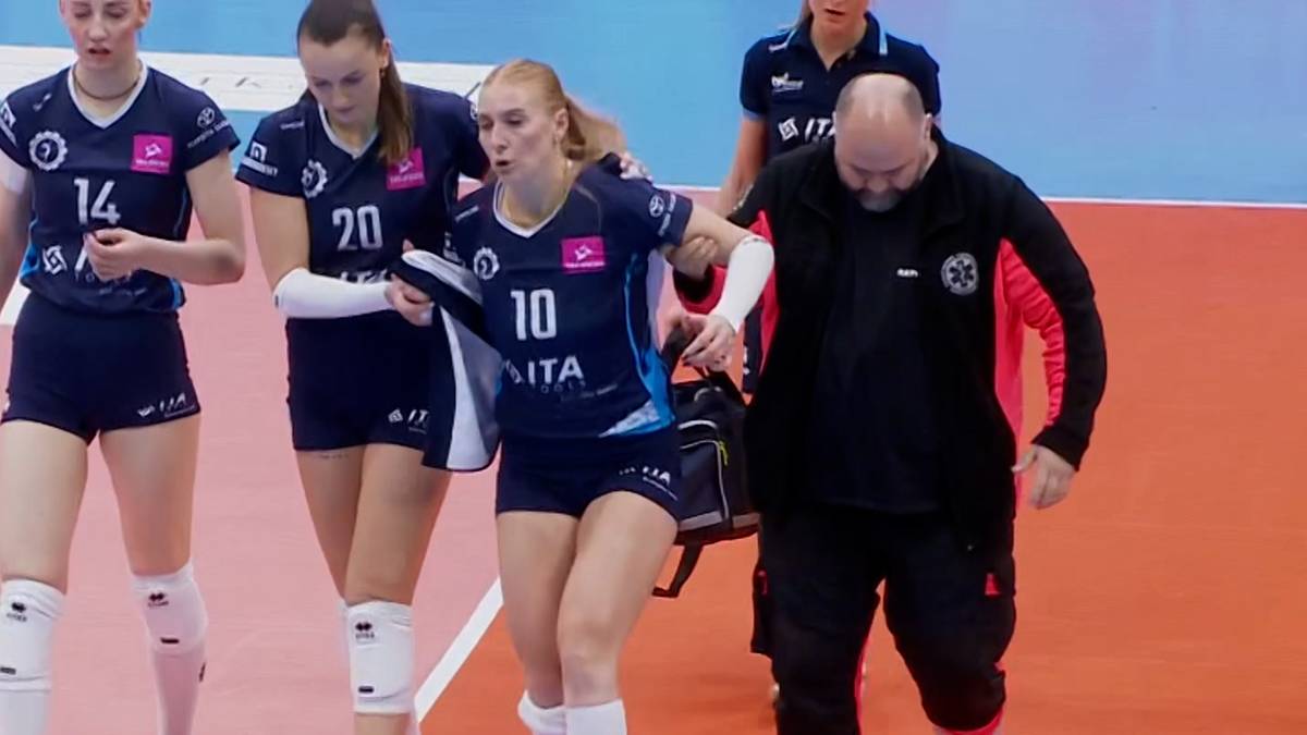 Siatkarki w niebiesko-białych strojach sportowych, jedna z nich z numerem 10 jest podtrzymywana przez koleżanki i ratownika medycznego.