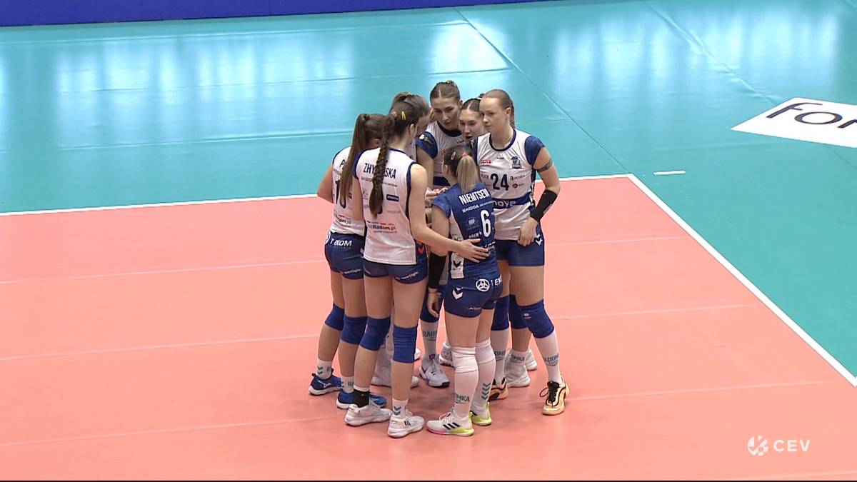 Siedem siatkarek MOYA Radomka Radom w niebieskich strojach stoi w k&oacute;łku na boisku do siatk&oacute;wki.