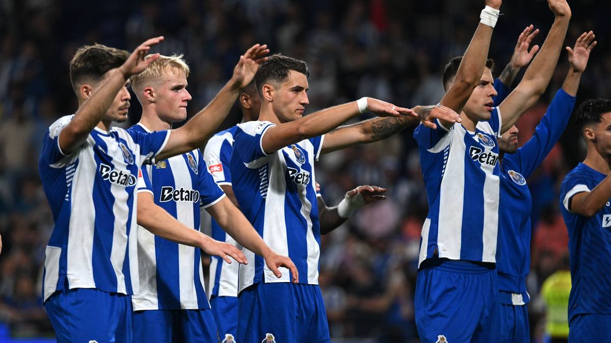 Grupa piłkarzy w niebiesko-białych strojach z białymi numerami na plecach, unoszą ręce w geście radości lub celebracji.