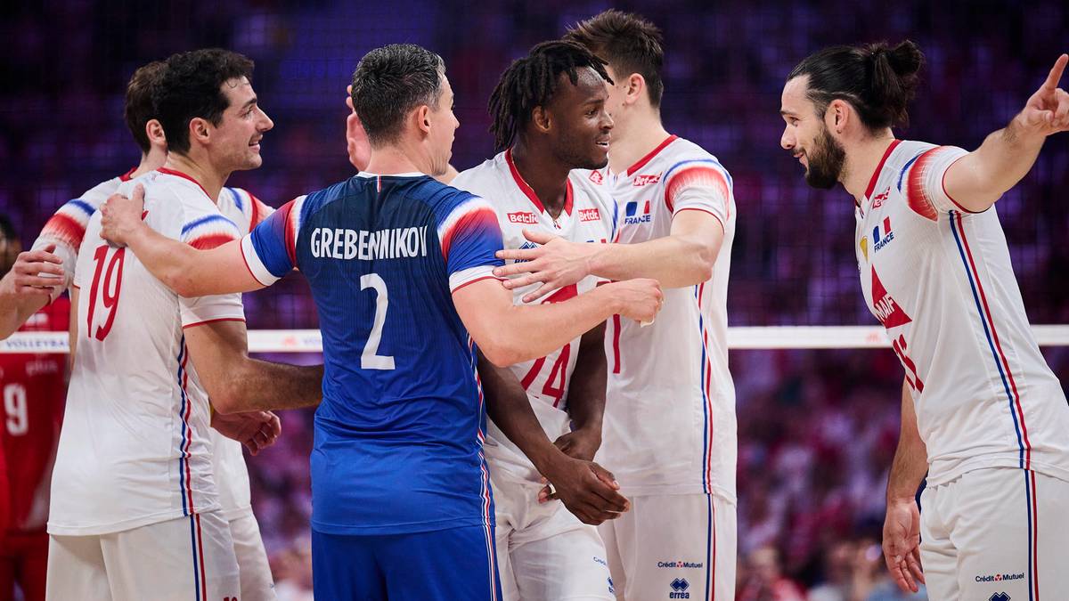 Siatkarze w biało-niebieskich strojach cieszą się po wygranej, jeden z nich trzyma rękę na ramieniu kolegi.