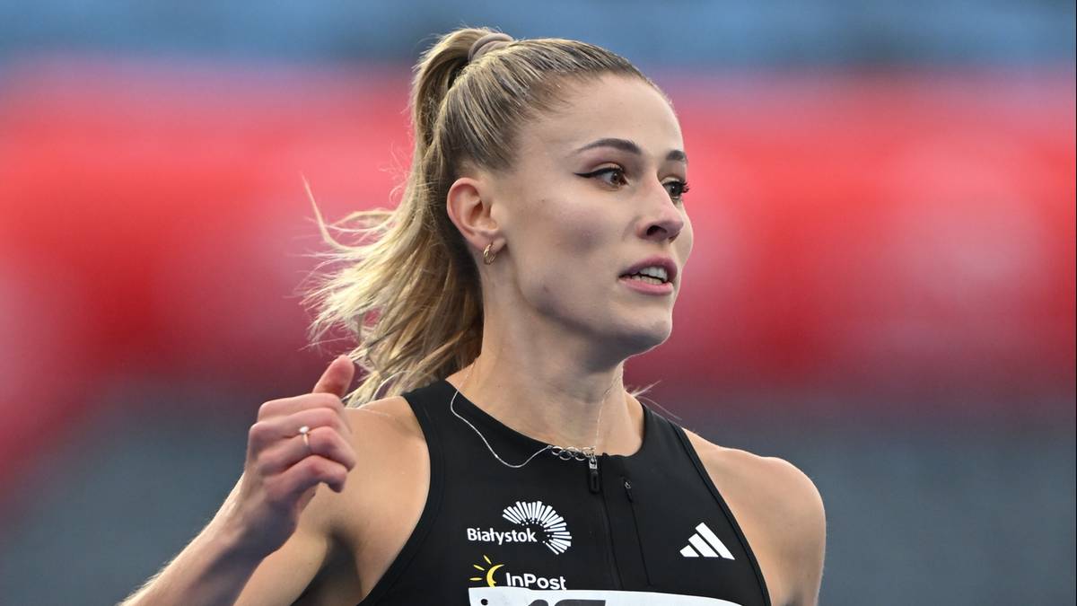 Portret zbliżeniowy lekkoatletki z blond włosami spiętymi w kucyk, kt&oacute;ra startuje w zawodach. Jest ubrana w str&oacute;j sportowy z widocznym logo "Białystok".