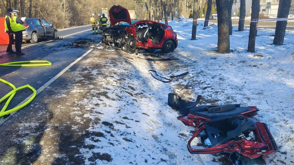 Miejsce wypadku drogowego z udziałem dw&oacute;ch samochod&oacute;w osobowych, w&oacute;z strażacki i służby ratownicze na drodze.