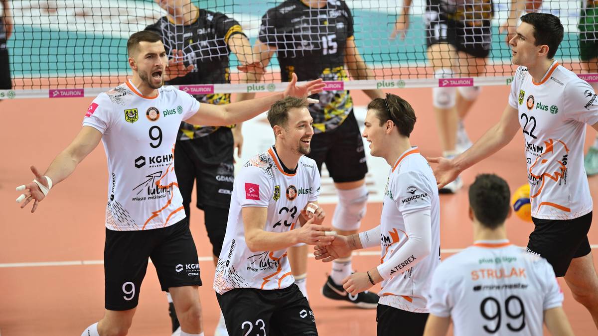 Siatkarze w białych koszulkach z numerami świętują zwycięstwo na boisku.
