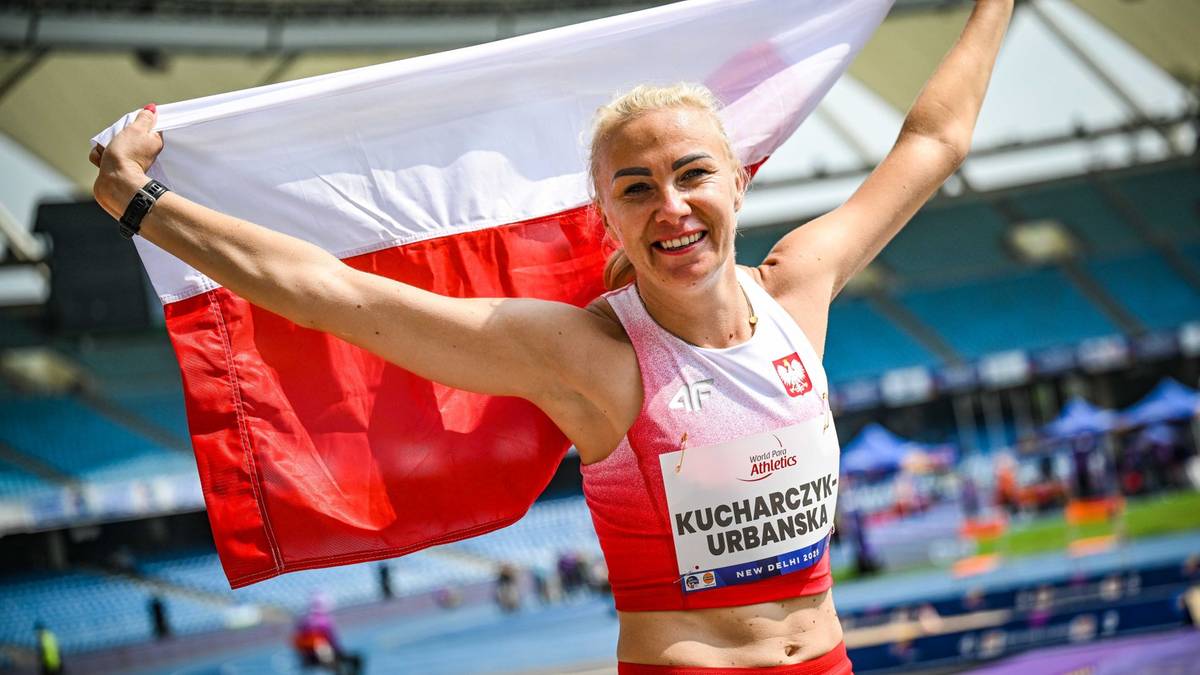 Uśmiechnięta lekkoatletka trzyma biało-czerwoną flagę Polski za plecami.