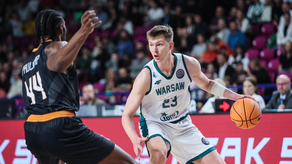 Dwóch koszykarzy podczas meczu, jeden w białym stroju z napisem "WARSAW" i numerem 23 prowadzi piłkę, drugi w czarnym stroju z numerem 44 próbuje mu ją odebrać.