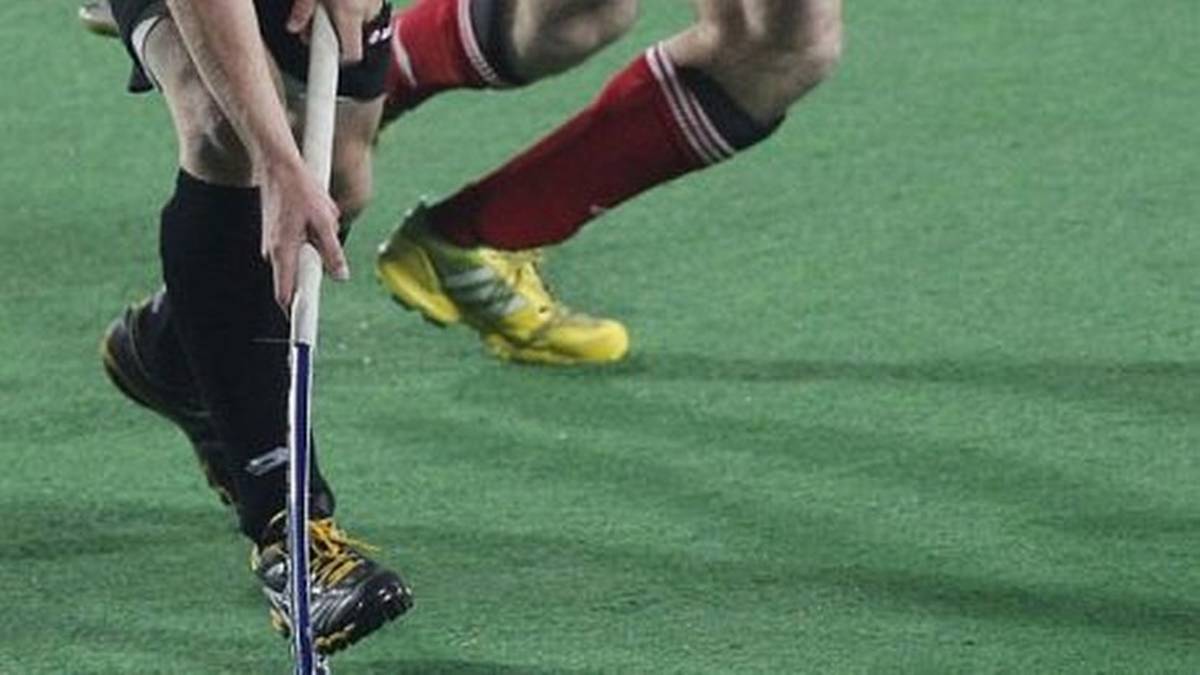 Dw&oacute;ch zawodnik&oacute;w hokeja halowego podczas meczu, widoczne nogi i kije.