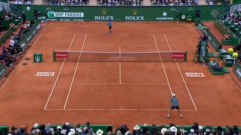 Kort tenisowy z czerwonej mączki z dwoma zawodnikami w akcji.