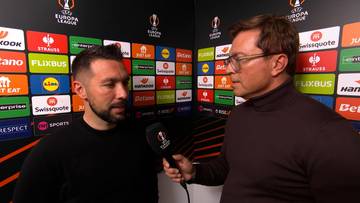 Dw&oacute;ch mężczyzn rozmawia na tle ścianki z logotypami sponsor&oacute;w Ligi Europy.