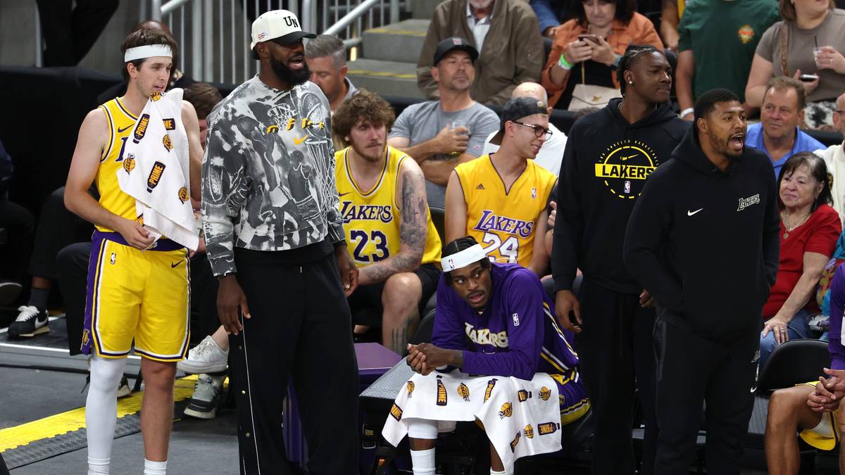 LeBron James w stroju Lakers, stojący i siedzący z drużyną na ławce rezerwowych.