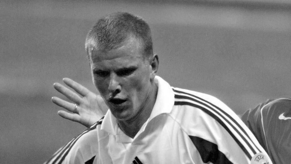 Portret piłkarza w czarno-białej tonacji, w koszulce sportowej z paskami na kołnierzu.