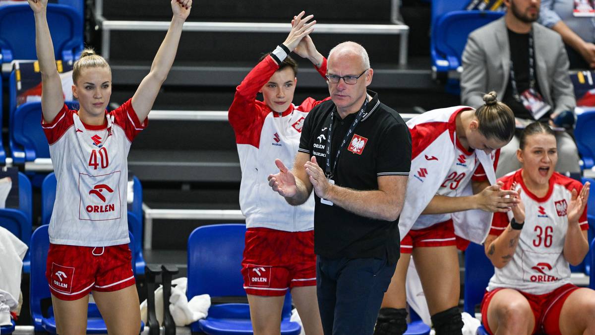 Trenerka piłki ręcznej stoi wśród czterech zawodniczek, które świętują.