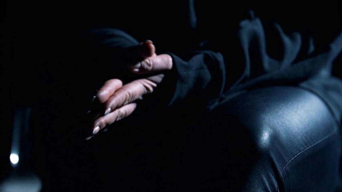 Dłoń zakrywająca twarz w mroku, symbolizująca desperację i ukrycie.