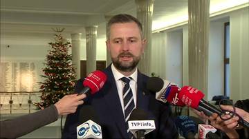 Władysław Kosiniak-Kamysz udziela wywiadu przed kilkoma mikrofonami, za nim stoi udekorowana choinka.