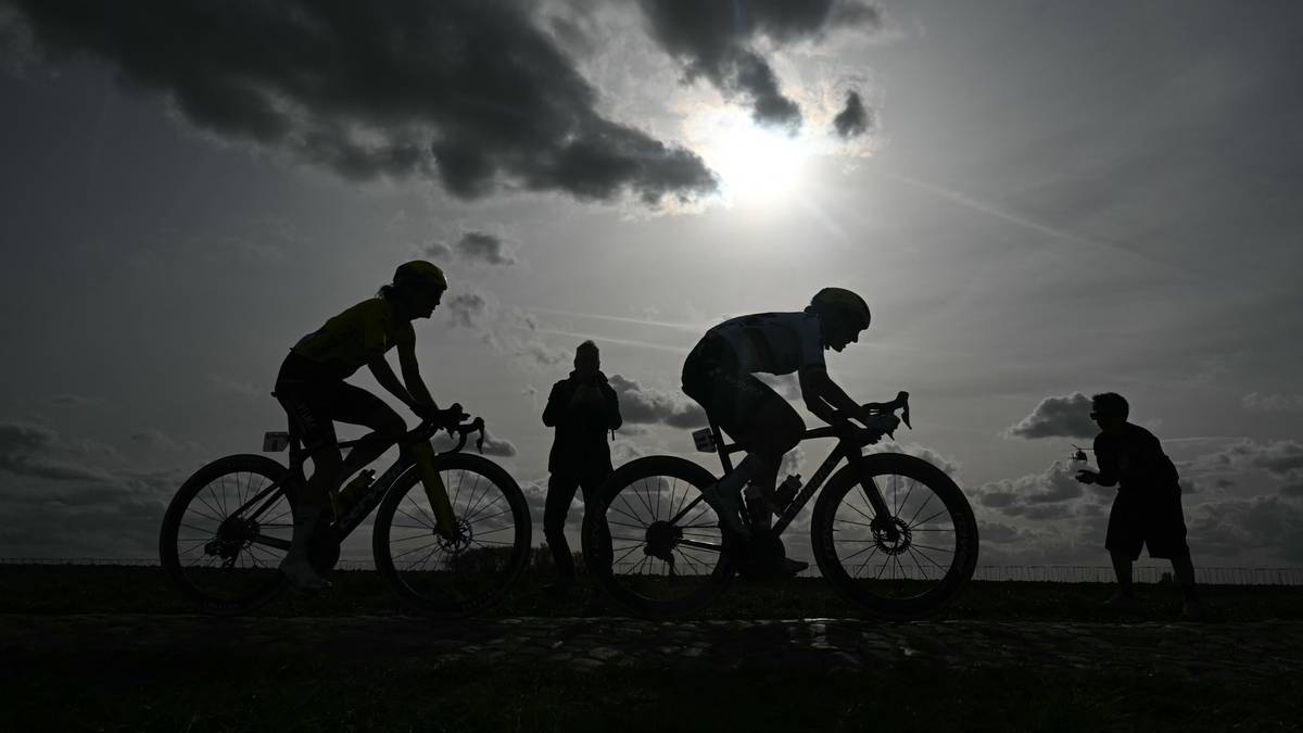 Sylwetki kolarzy na tle zachodzącego słońca.