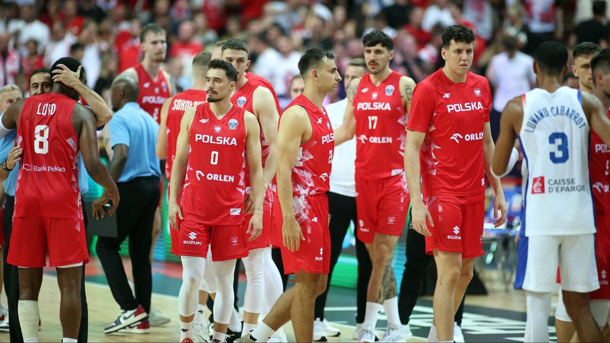 Drużyna koszykarzy Polski w czerwonych strojach wychodzi z boiska po przegranym meczu z Francją. Gracze mają smutne miny.