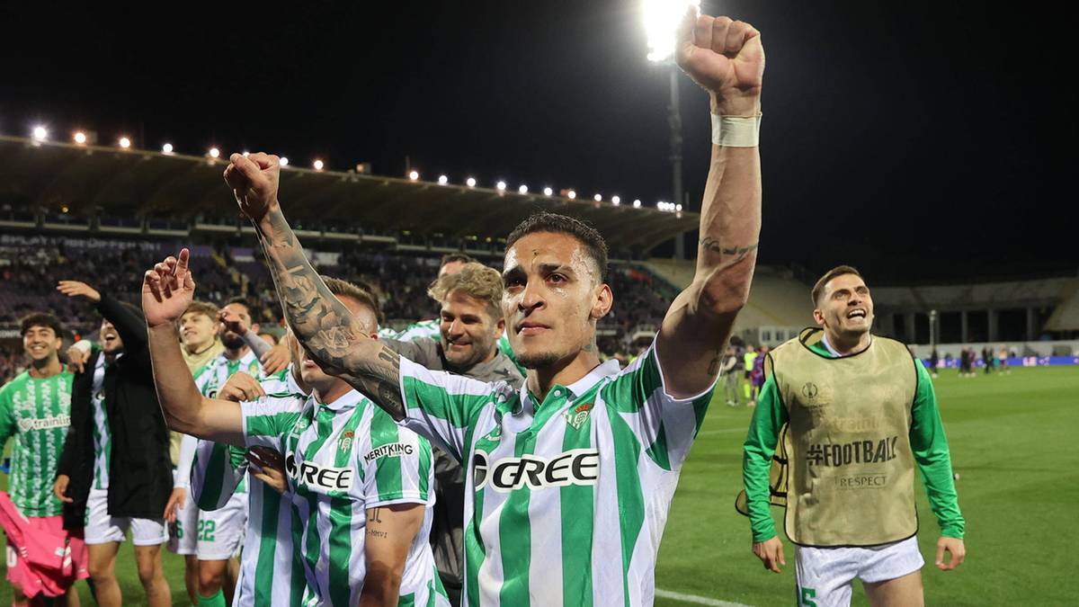 Piłkarze Real Betis świętują zwycięstwo na boisku, jeden z nich wznosi ręce w geście triumfu.