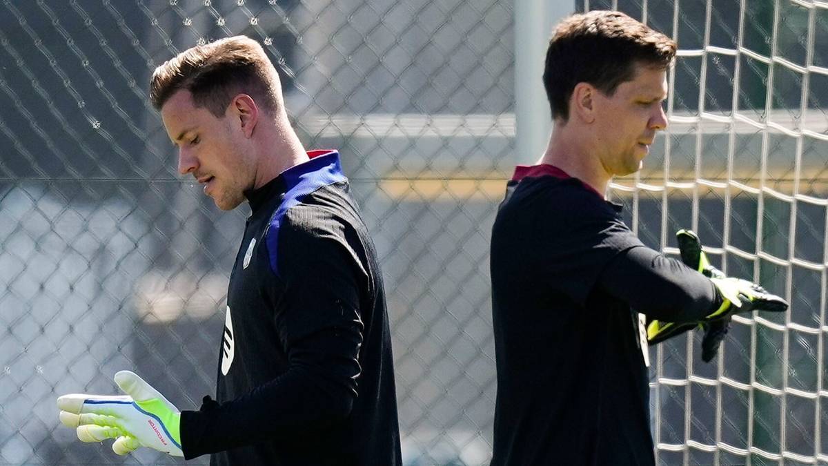 Dwóch bramkarzy w czarnych strojach i rękawicach bramkarskich stoi obok siebie plecami do siebie, z widokiem na siatkę bramki.