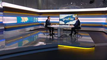 Dwóch mężczyzn siedzi przy okrągłym stole w studiu telewizyjnym. Na ekranie za nimi wyświetlany jest napis "graffiti".