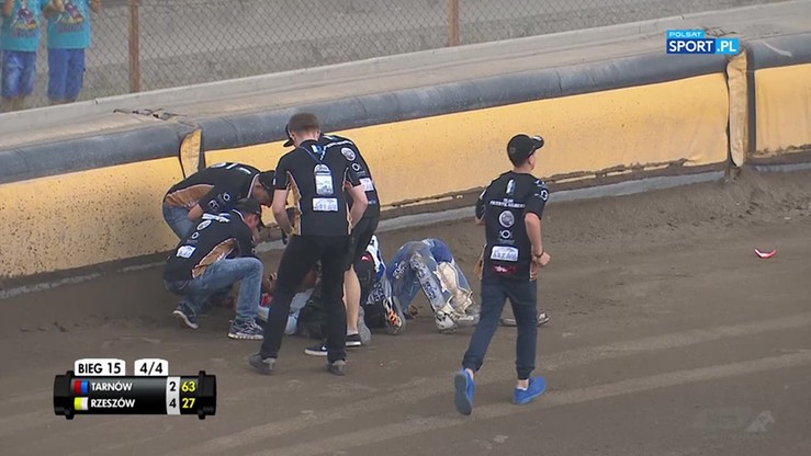 Zawodnicy żużlowi pomagają koledze po upadku na torze.