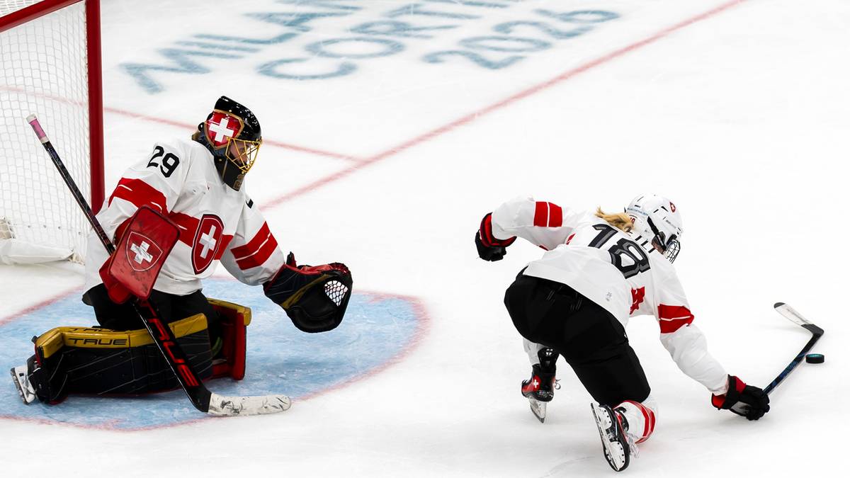Hokeistka w białym stroju z czerwonym krzyżem na piersi i bramkarz w czerwono-białym stroju na lodowisku.