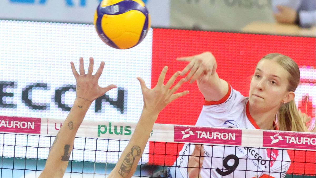 Siatkarka wykonująca atak w meczu siatkówki, z piłką nad głową i dłonią wyciągniętą do zagrania.