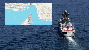 Okręt wojenny na morzu z mapą cieśniny Ormuz w tle.