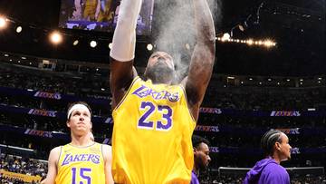 Koszykarz LeBron James z numerem 23 na koszulce sypie talk na dłonie przed meczem.