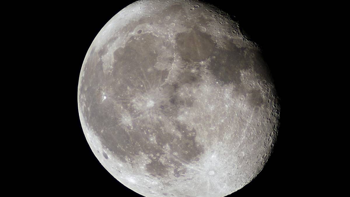 Zbliżenie na Księżyc z widocznymi kraterami i morzami księżycowymi na czarnym tle.