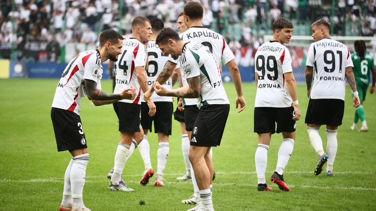 Piłkarze Legii Warszawa w białych strojach świętują zwycięstwo na boisku.