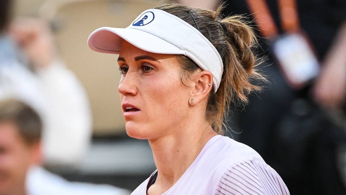 Portret tenisistki w białej czapce z daszkiem i różowym daszkiem, patrzącej w bok z lekko zmarszczonymi brwiami.