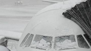Samolot pokryty śniegiem na płycie lotniska.