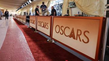 Znak z napisem "OSCARS" na tle czerwonego dywanu i element&oacute;w scenografii gali.
