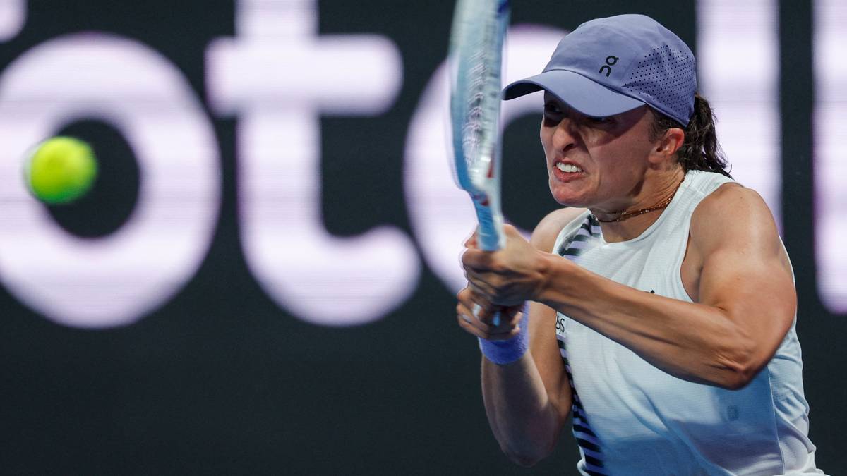 Tenisistka Iga Świątek podczas uderzenia piłki rakietą, skupiona na grze.