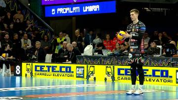 Siatkarz w stroju sportowym z piłką w ręku na boisku.