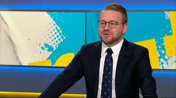 Mężczyzna w garniturze i okularach wypowiada się w studio telewizyjnym.
