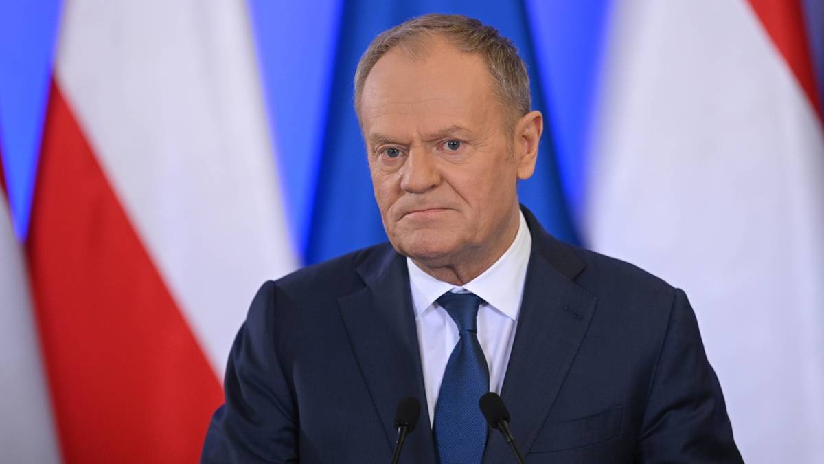 Premier Donald Tusk na tle flagi Polski i Unii Europejskiej.