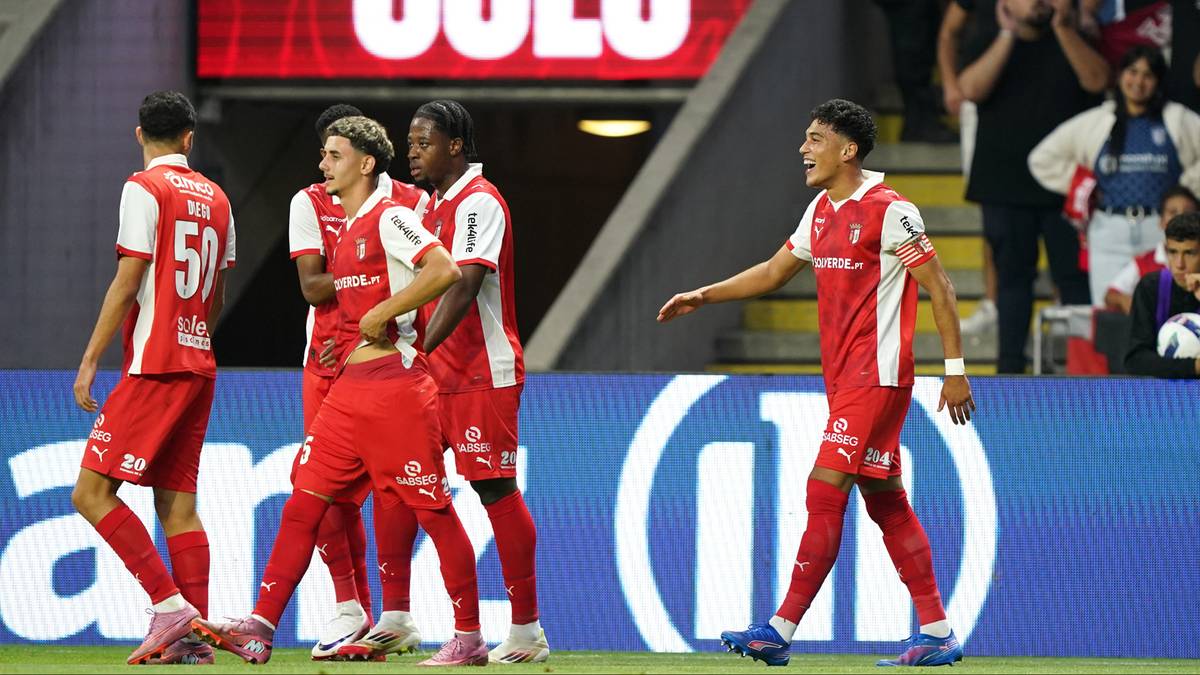 Drużyna piłkarska w czerwonych strojach świętuje bramkę na boisku.