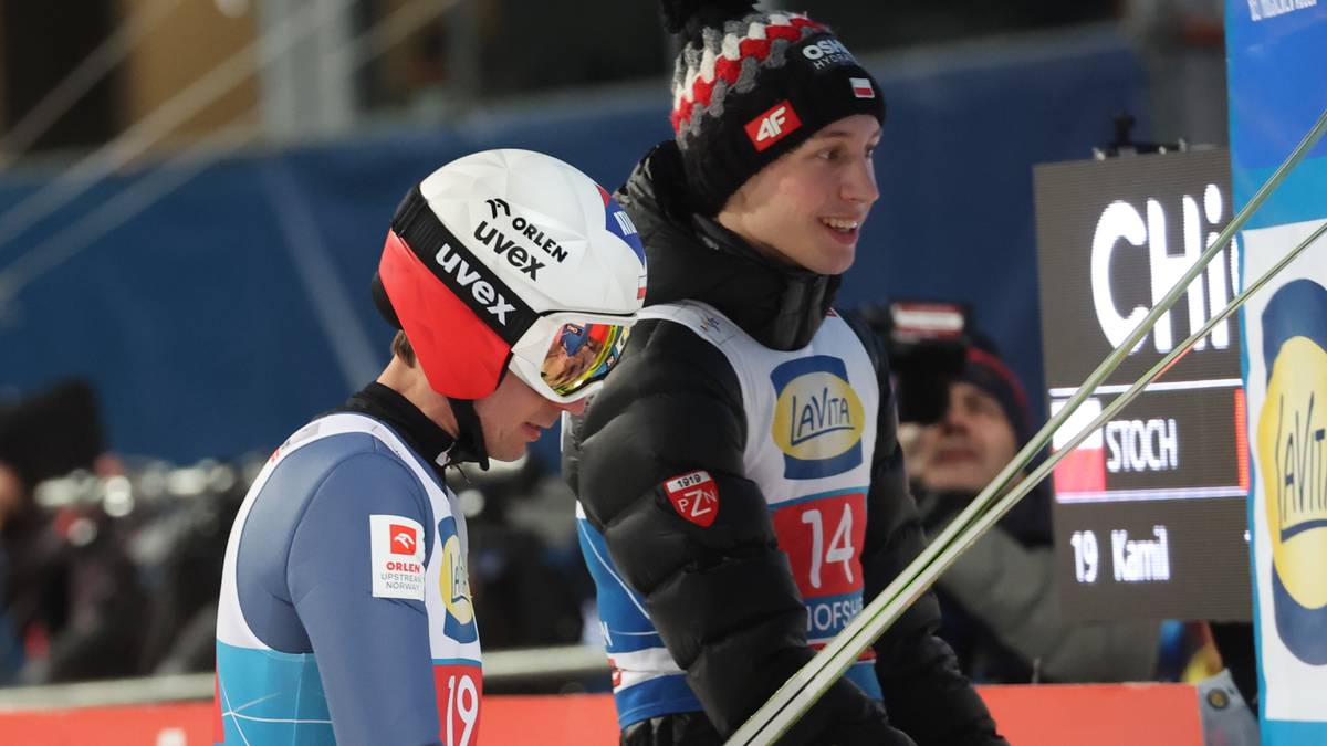 Dw&oacute;ch skoczk&oacute;w narciarskich w kaskach i kombinezonach.