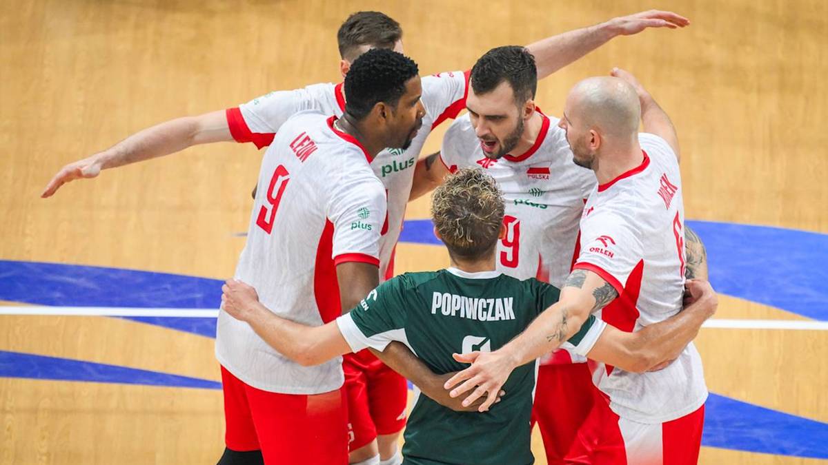 Grupa zawodników w biało-czerwonych strojach radośnie celebruje coś, otaczając jednego gracza w zielonej koszulce.