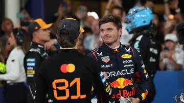 Dwóch kierowców Formuły 1 w kombinezonach wyścigowych, Max Verstappen i Lando Norris, rozmawia ze sobą po zawodach.