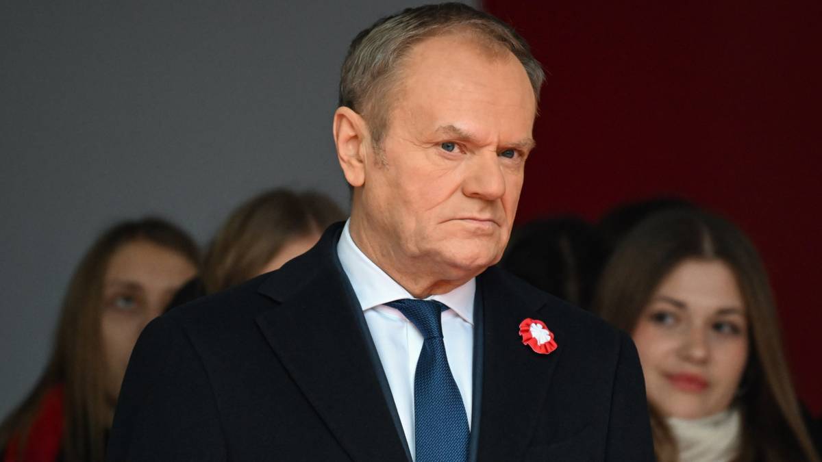 Premier Donald Tusk w garniturze z niebieskim krawatem, z poważnym wyrazem twarzy