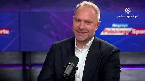 Mężczyzna w garniturze siedzi przed mikrofonem w studiu telewizyjnym, w tle logo Polsat Sport.