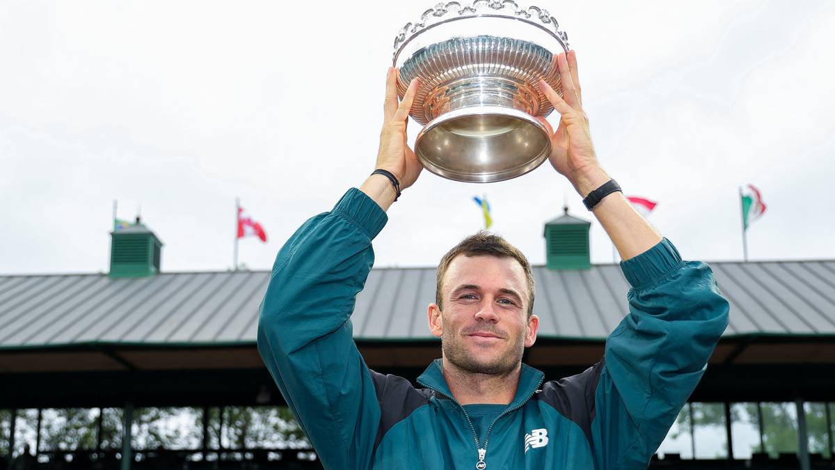 Tommy Paul trzymający trofeum tenisowe nad głową.