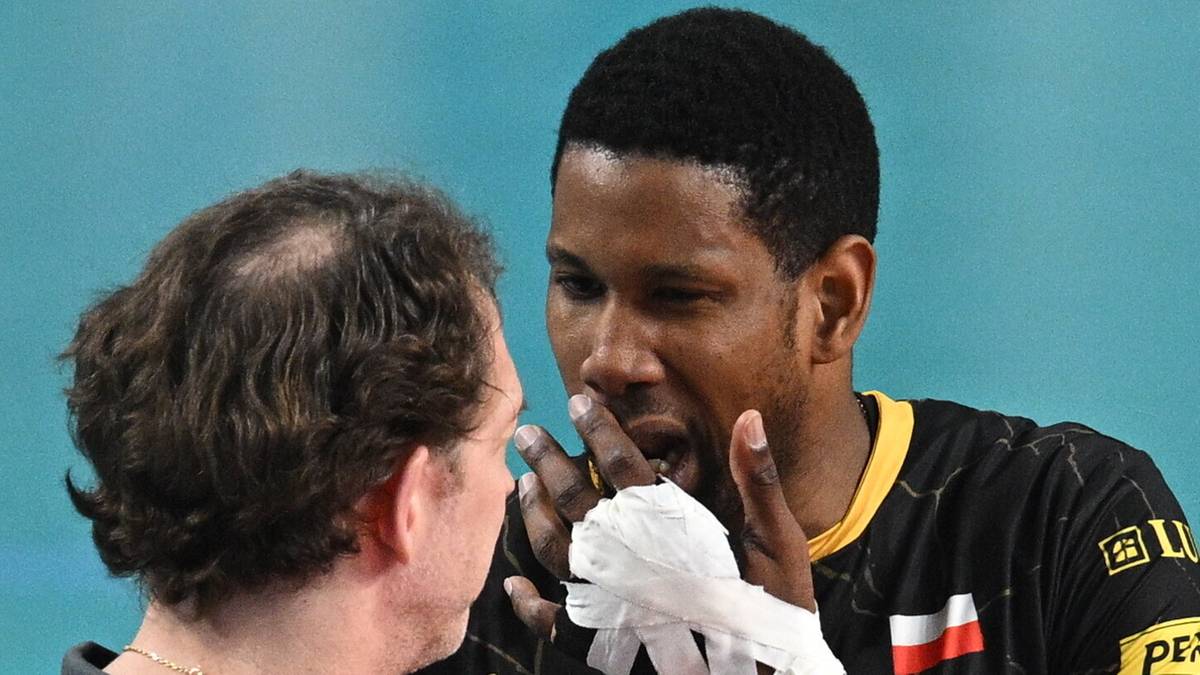 Dw&oacute;ch siatkarzy rozmawia ze sobą na boisku, jeden z nich ma opatrzoną rękę.